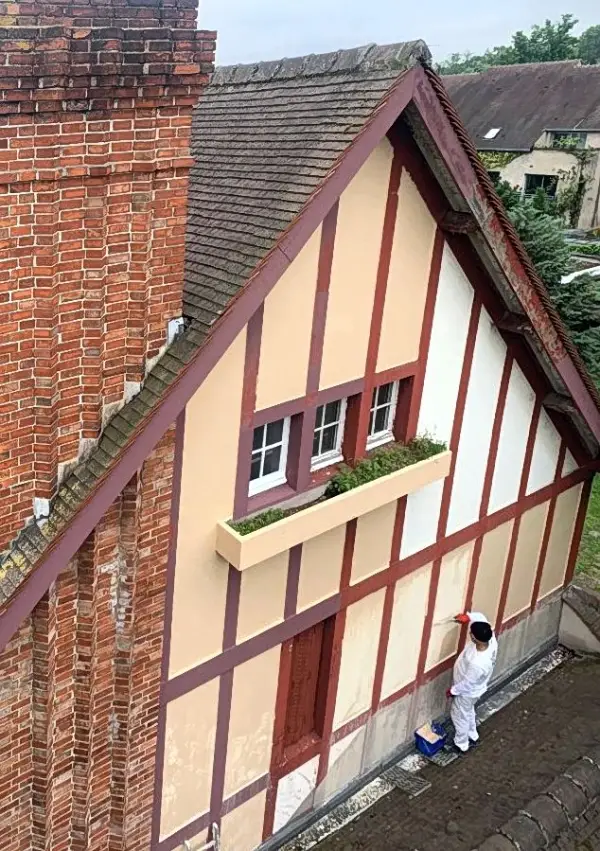Ravalement et peinture intérieur - extérieur 2 Artisan façadier peignant un pignon à colombages près d’une cheminée en briques, ravalement de façade à Versailles (Yvelines).